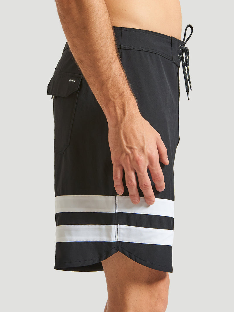 Boardshorts Phantom Hurley preto com duas listras horizontais brancas na perna, bolso traseiro com aba e ajuste frontal por cordão. Design esportivo.