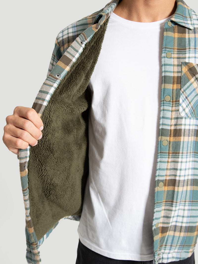 Camisa flanela xadrez em tons de azul, amarelo e branco, com forro interno verde aveludado. Possui botões frontais e bolso no peito.
