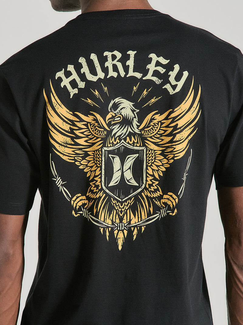 Camiseta preta manga curta estampa nas costas, destacando uma águia dourada estilizada, escudo central e o texto “Hurley” em letras brancas.