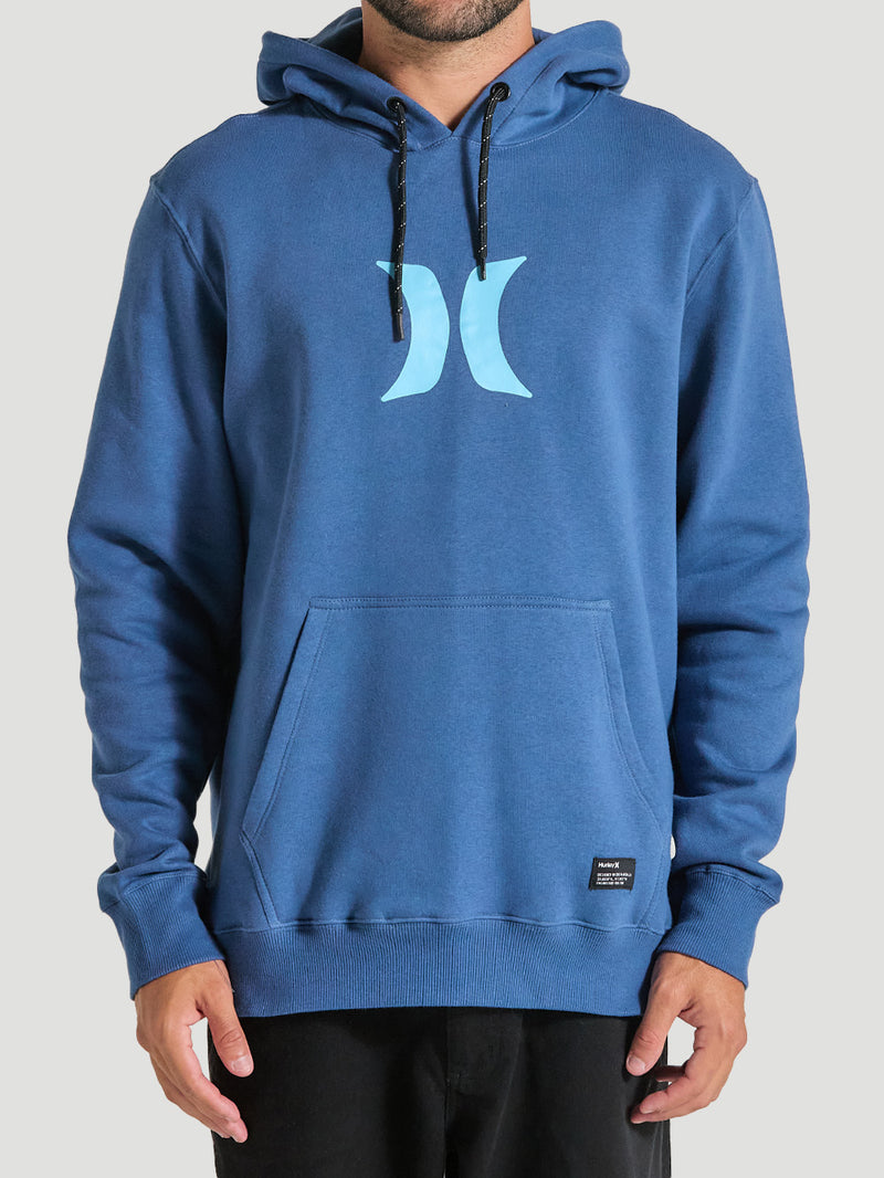 Homem vestindo um moletom canguru azul marinho básico Hurley, com bolso frontal, capuz ajustável com cordões pretos e logo azul claro no peito.