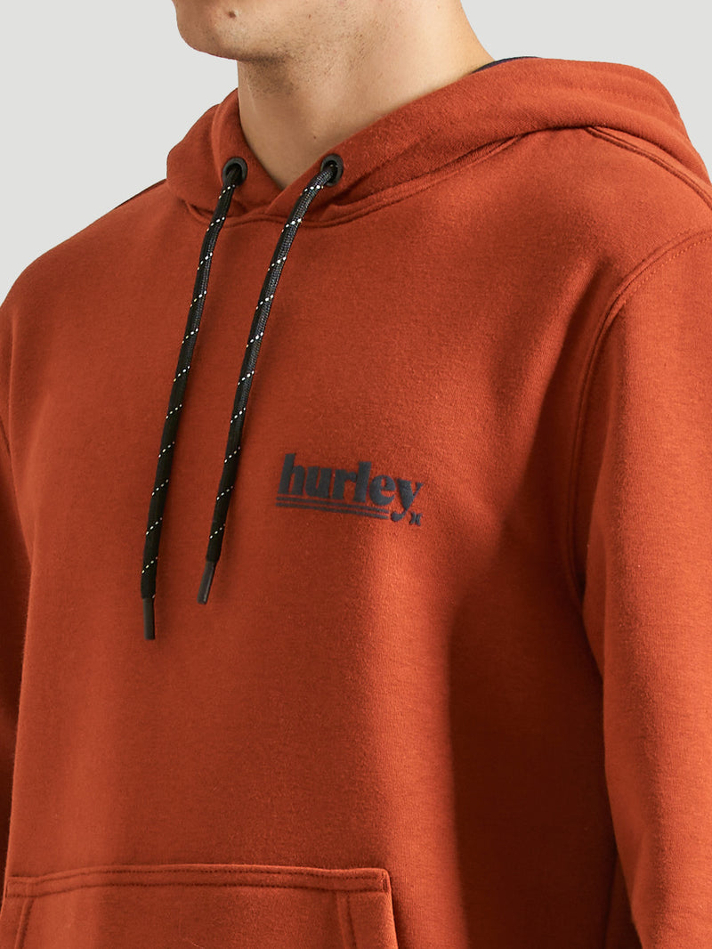 Detalhe do moletom canguru vermelho da Hurley, destacando o capuz ajustável com cordão preto e o logo discreto da marca em relevo no peito. O tecido apresenta textura suave e acabamento refinado.