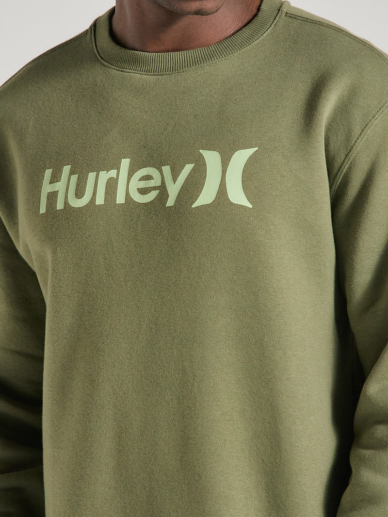 Close de um moletom careca verde militar felpado Hurley, com logo verde claro centralizado no peito, tecido macio e acabamento canelado na gola.