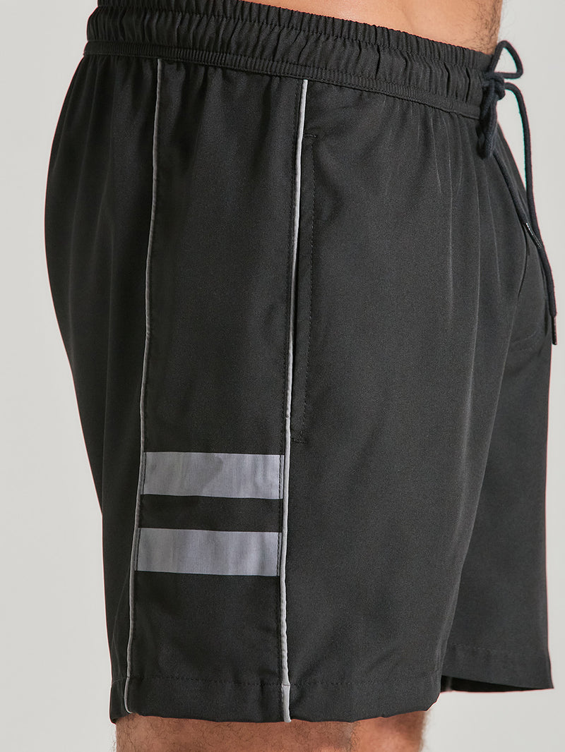 Shorts tactel preto 17 polegadas, cós elástico com ajuste por cordão, detalhes de duas listras reflexivas cinzas e acabamento discreto.