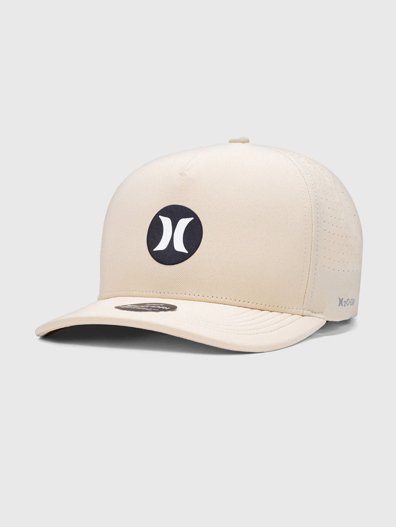 Boné bege Hurley com aba curva, logo circular preto e branco centralizado e acabamento perfurado nas laterais para ventilação. Moderno e confortável.