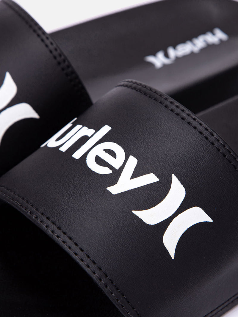 Chinelo slide preto com tira larga, logotipo Hurley em branco e acabamento em costura reforçada. Design casual e confortável.