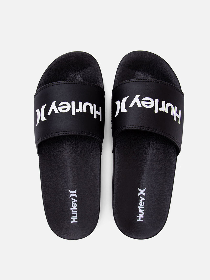 Chinelo slide preto Hurley com tira larga emborrachada, logotipo branco centralizado e solado texturizado para conforto e aderência.