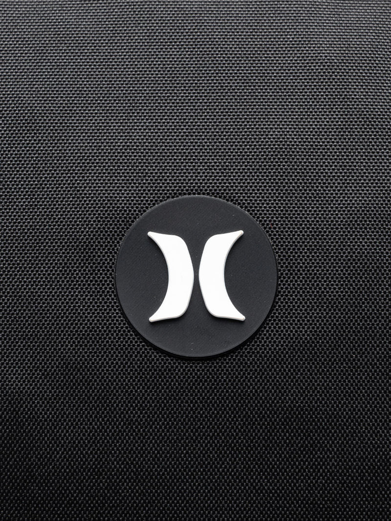 Close de logo branco na mochila Hurley em destaque no tecido preto texturizado. Design minimalista e moderno.