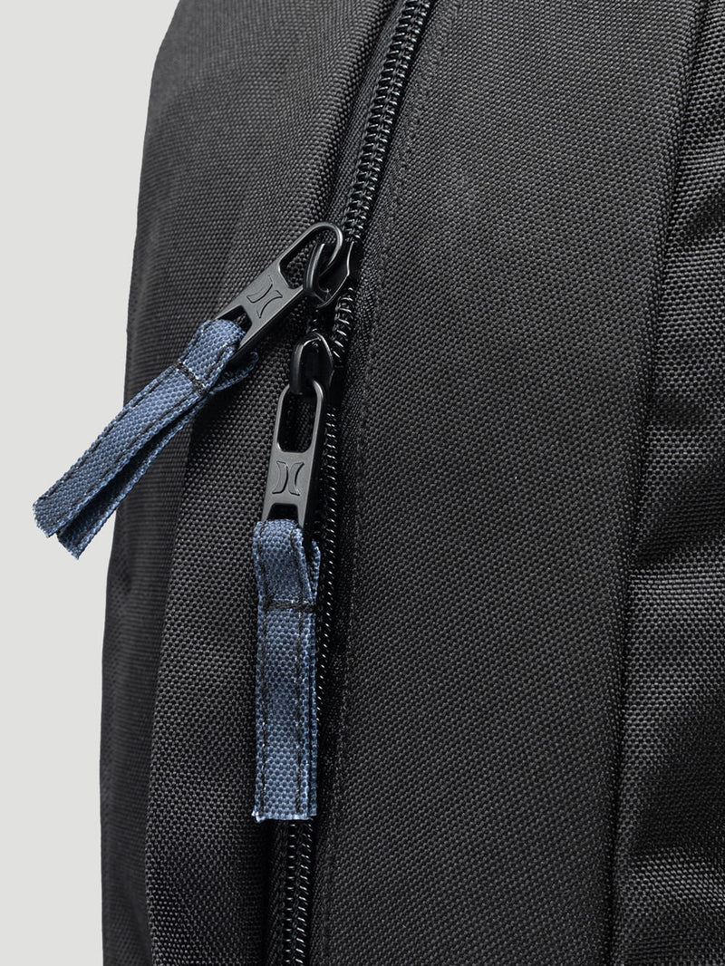 Fecho em zíper preto com puxadores reforçados na mochila Hurley, detalhes em tecido azul escuro com costura visível. Design funcional e durável.
