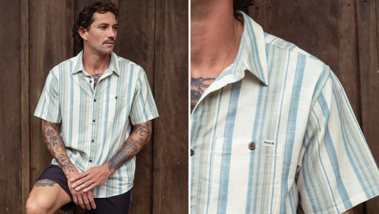 Modelo em fundo amadeirado vestindo a camisa manga curta listrada off white listrada Hurley ONE&ONLY Lido Stripe.