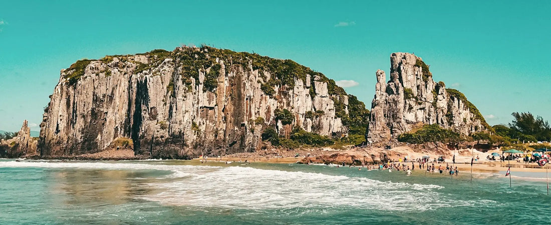 Imagem da Praia de Torres, com pedras ao fundo e um mar e um céu bem azuis.