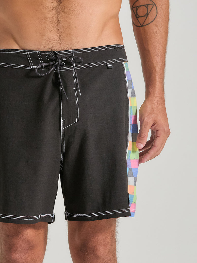 Homem vestindo boardshorts phantom 16 polegadas preto com padrão xadrez colorido nas laterais. O design inclui cintura com amarração e costura branca contrastante.