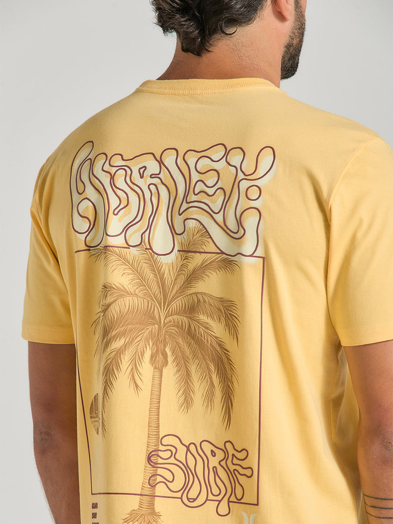 Esta camiseta amarela manga curta estampa relevo apresenta uma arte nas costas que combina elementos tropicais e surfistas. O destaque do design é uma palmeira central, enquadrada por linhas minimalistas e complementada com as palavras "Hurley" e "Surf" em uma fonte estilizada que transmite vibração e descontração.
