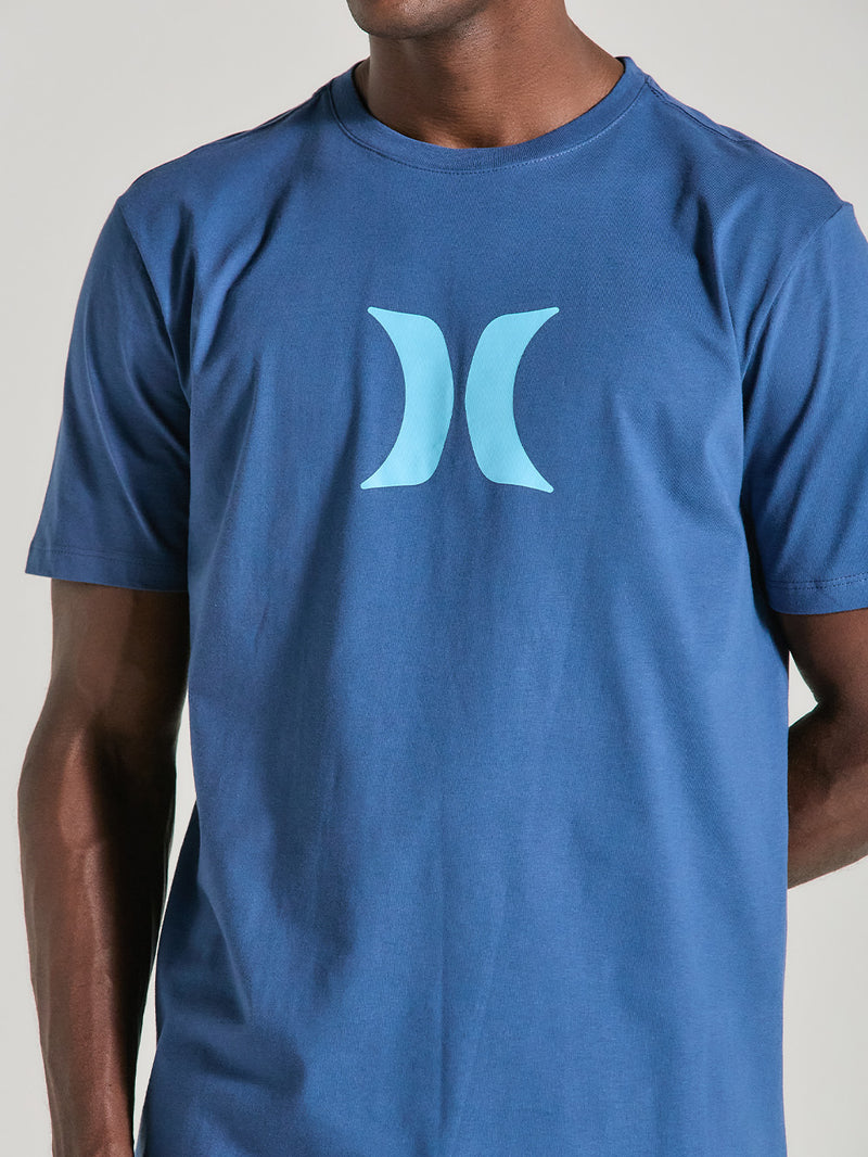 Camiseta azul manga curta básica com estampa minimalista azul clara no centro, tecido liso, gola redonda e caimento reto, em fundo neutro.