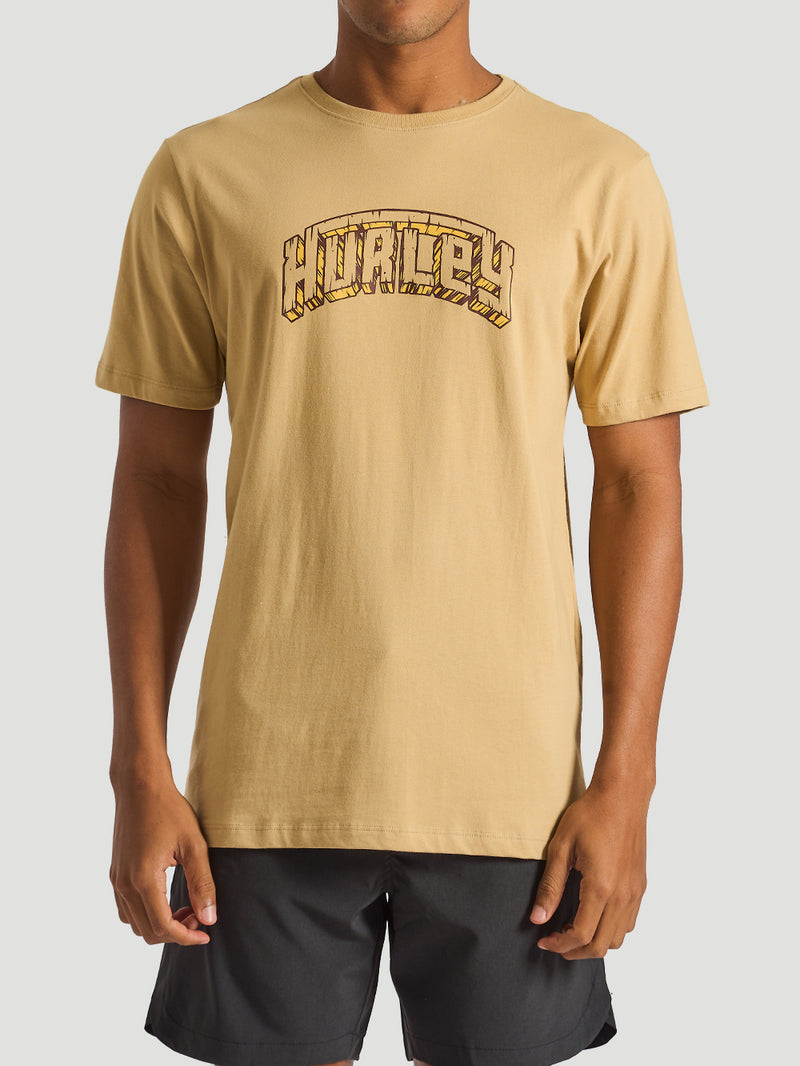 Homem vestindo camiseta bege masculina com logo Hurley estilizado no peito, combinando conforto e estilo casual.