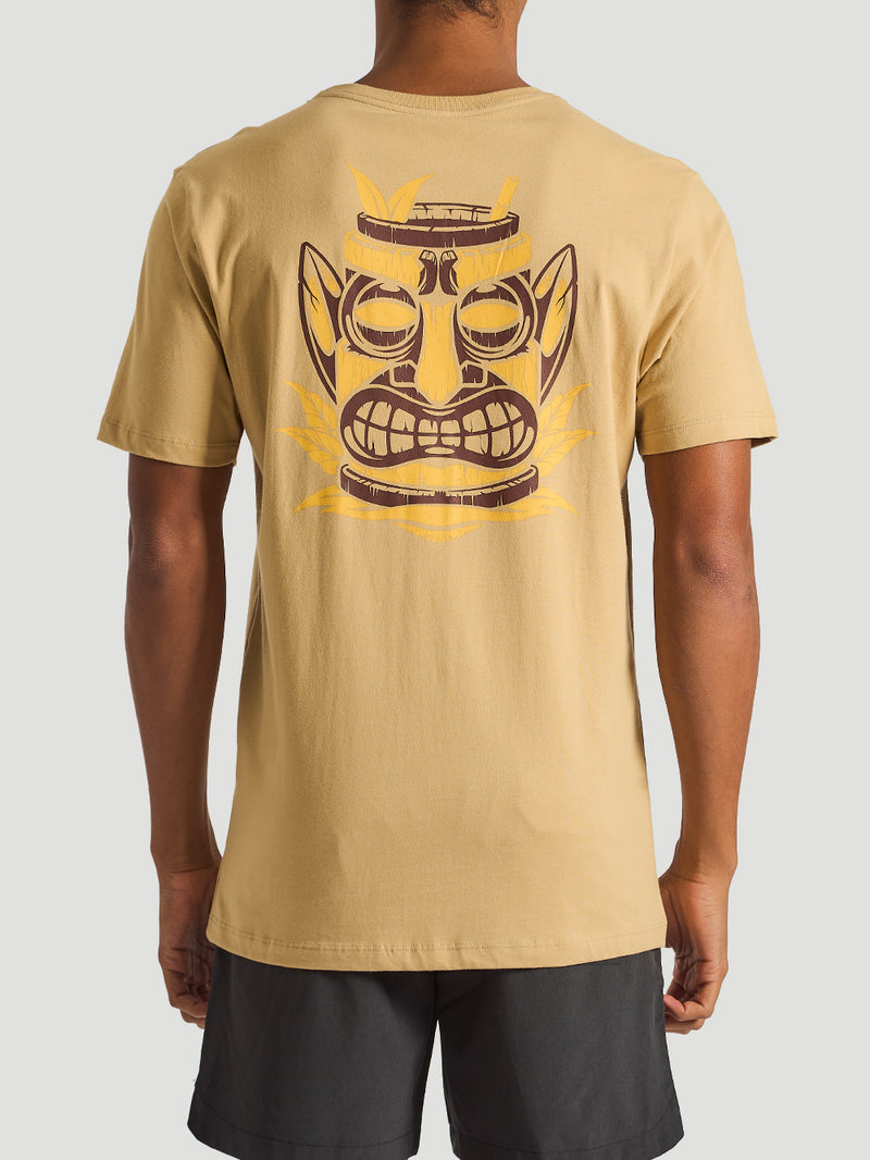 Homem vestindo camiseta bege masculina com estampa Tiki nas costas, combinando estilo descontraído com inspiração cultural.