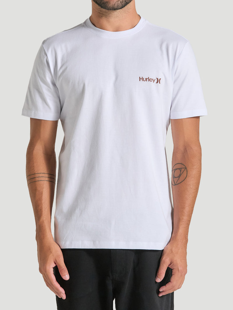 Homem vestindo camiseta branca com estampa, de gola redonda e mangas curtas. Possui o logotipo Hurley em marrom discreto no lado esquerdo do peito.