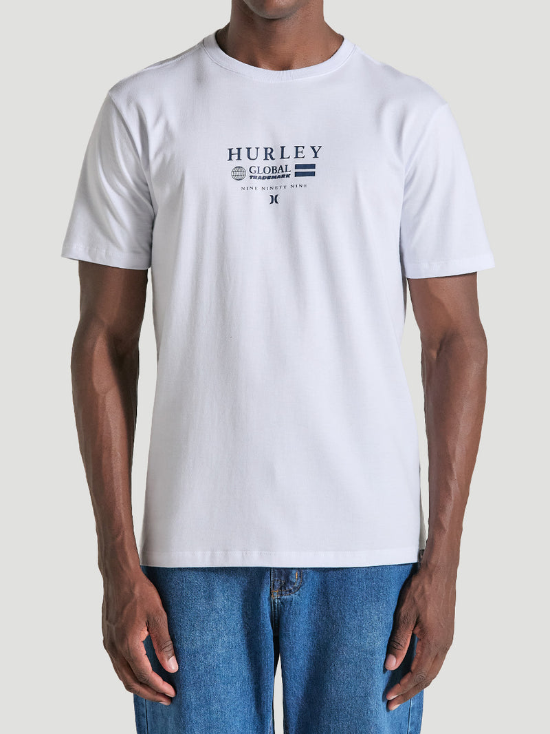 Homem veste uma camiseta branca estampa frontal manga curta minimalista. O design inclui o texto "Hurley Global Trademark" em azul escuro.