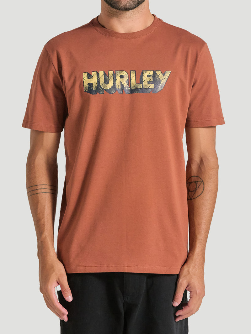 Camiseta marrom de manga curta estampada. A estampa possui o logotipo Hurley na frente, o tecido é de algodão.