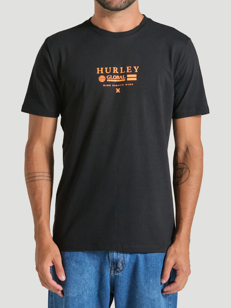 Homem veste camiseta preta estampa frontal manga curta com dizeres em laranja. O design inclui o texto "Hurley Global Trademark" e elementos gráficos minimalistas.