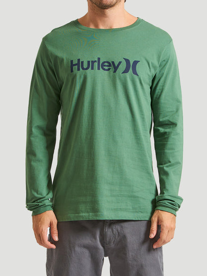 Camiseta verde militar manga longa com estampa do logo "Hurley" em azul escuro, combinada com calça cinza. Fundo cinza claro.