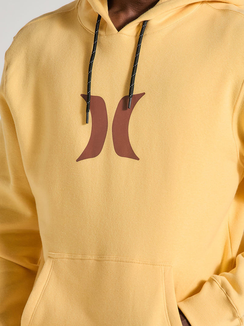 Close do moletom canguru amarelo básico Hurley Icon, com logo marrom centralizado no peito, bolso frontal, capuz ajustável com cordões pretos e acabamento minimalista.