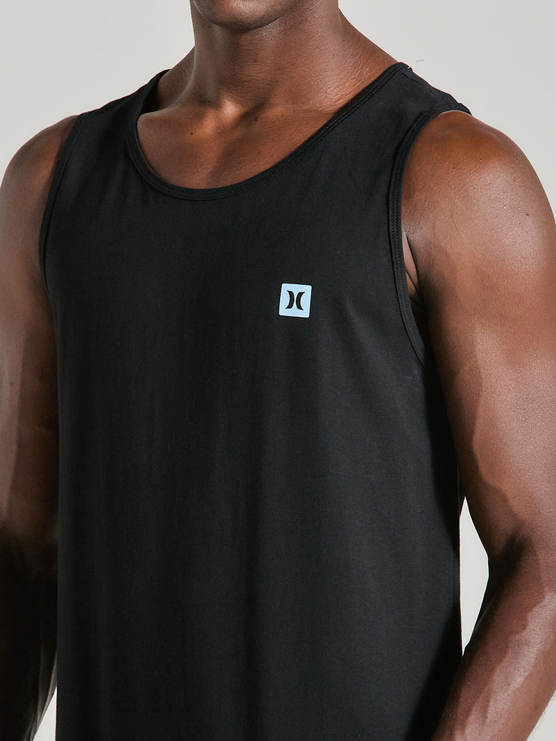 Homem vestindo uma regata preta esportiva com logo azul discreto no lado esquerdo do peito. A peça possui tecido leve e modelagem confortável.