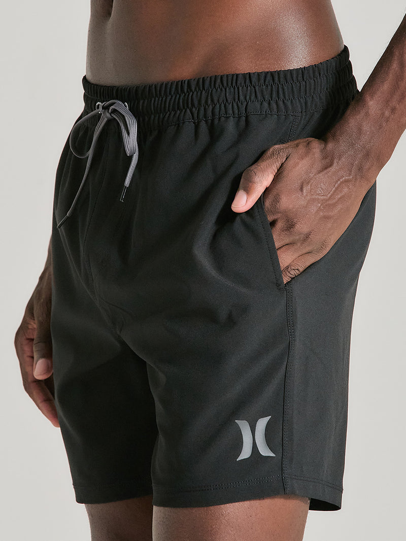 Homem usando shorts phantom 17 polegadas preto Hurley, com cós de elástico, cordão cinza ajustável, bolso lateral e logo reflexivo na perna direita.
