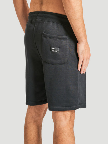 Bermuda moletom preta com bolso traseiro aplicado, detalhe de etiqueta discreta no bolso, cós elástico e caimento reto.