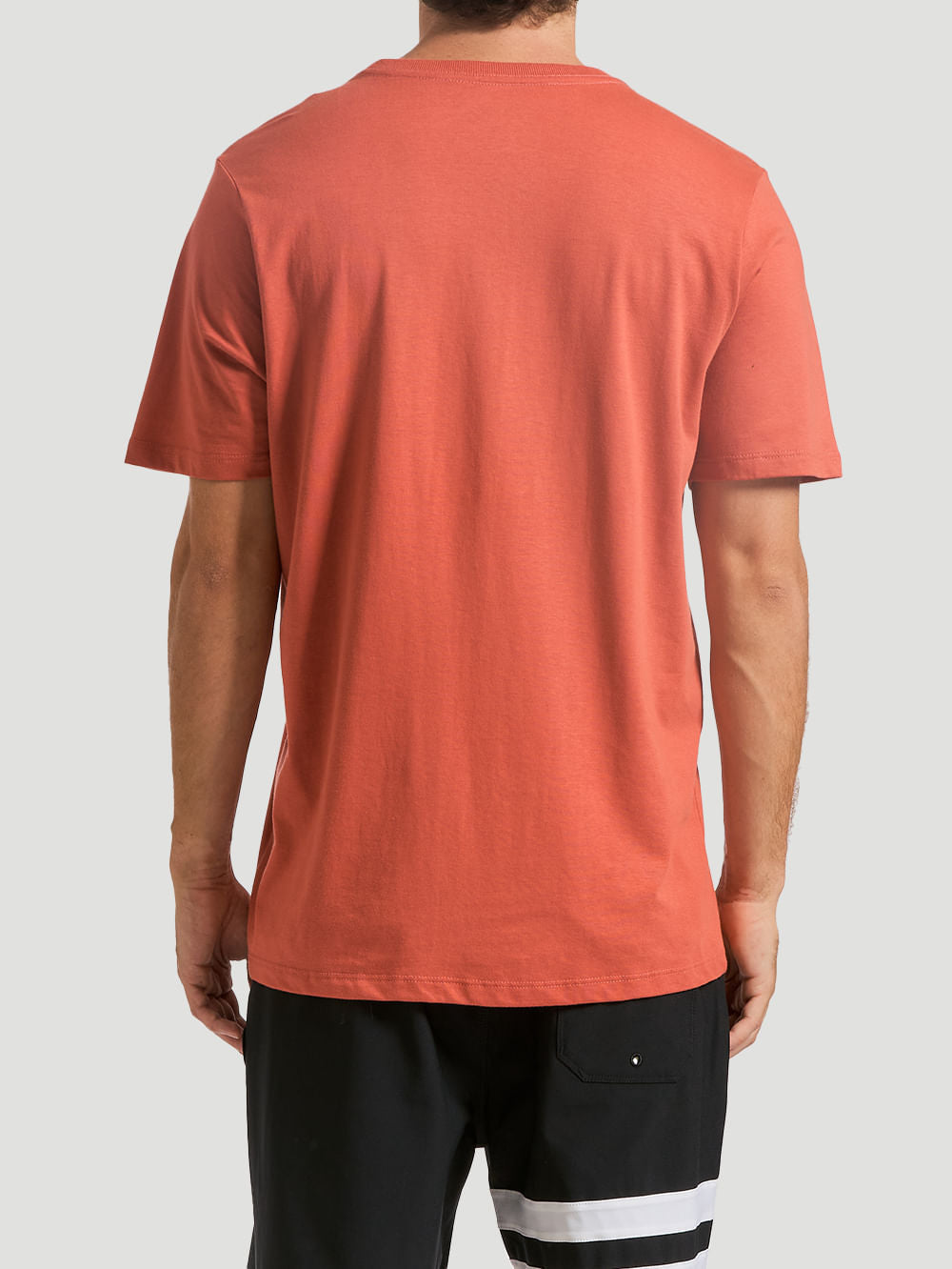 Camiseta estampada algodão marrom vista de costas, combinada com shorts preto com detalhes brancos. Fundo claro e neutro.