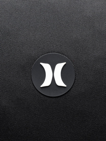 Close de logo branco na mochila Hurley em destaque no tecido preto texturizado. Design minimalista e moderno.