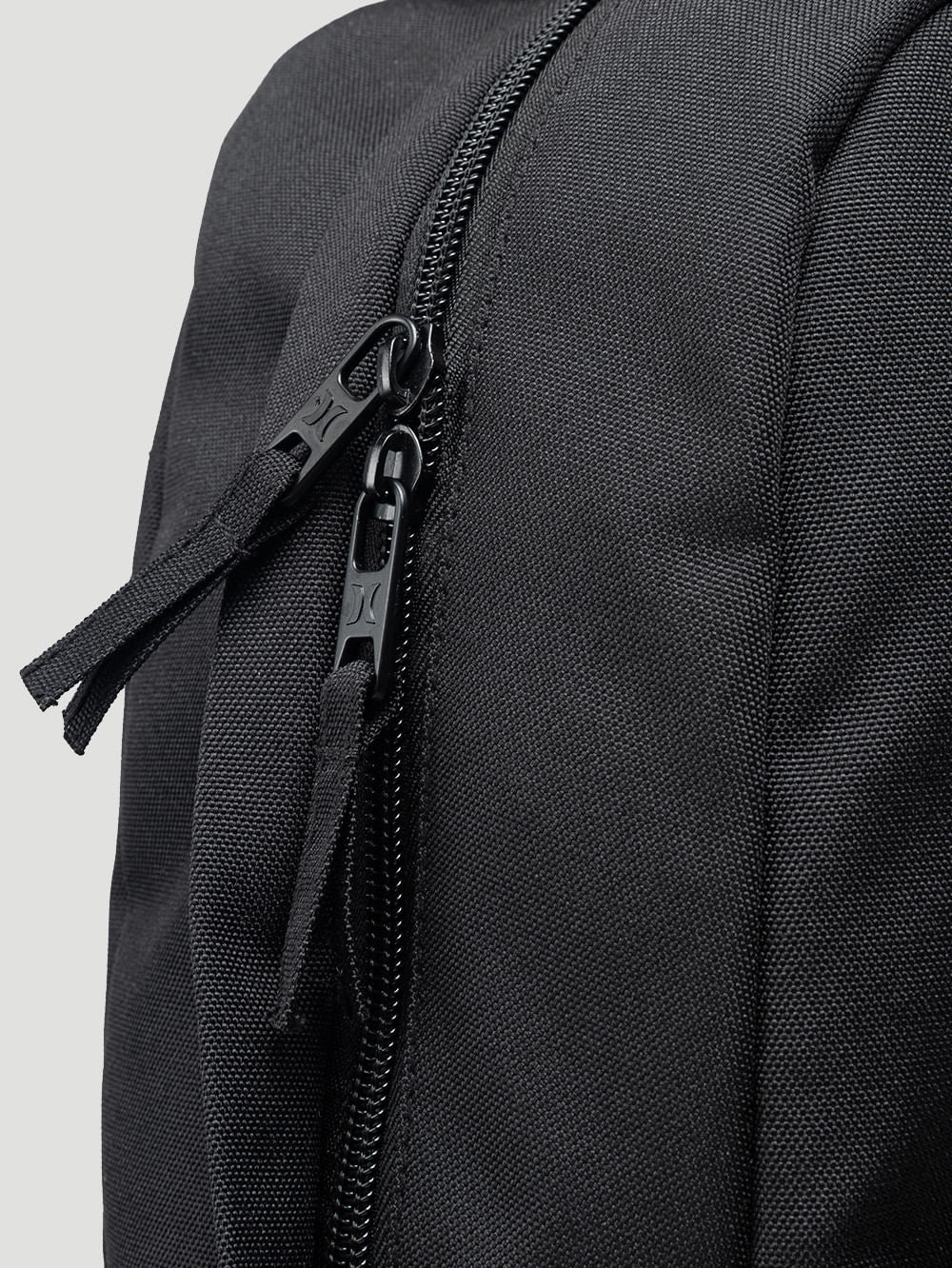 Detalhe de zíper duplo em mochila para notebook preta, com costuras reforçadas e material resistente, ideal para o dia a dia ou trabalho.